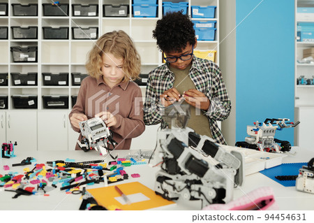 Two intercultural schoolboys connecting together details during construction 94454631