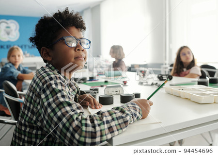 Clever schoolboy in eyeglasses and checkered shirt making notes in copybook Clever schoolboy in eyeglasses and checkered shirt making notes in copybook 94454696