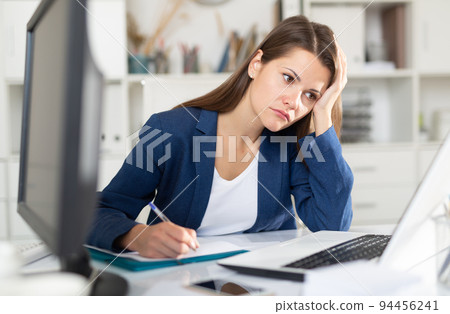 Upset woman working with laptop and papers Upset woman working with laptop and papers 94456241