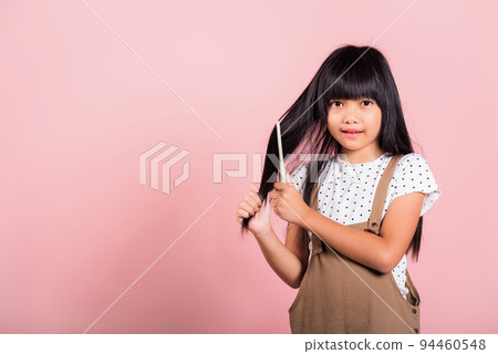 Asian little kid 10 years old hold comb brushing her unruly she touching her long black hair 94460548
