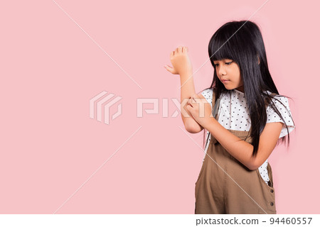 Asian little kid 10 years old scratching itch arm from a mosquito bite 94460557