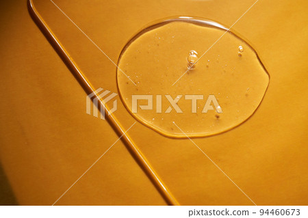 A drop of body gel or shampoo on a yellow saturated background. Texture. A drop of body gel or shampoo on a yellow saturated background. Texture. 94460673