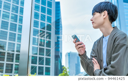 Young businessman operating a smartphone in office casual Young businessman operating a smartphone in office casual 94461425