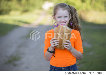 Happy little girl on the street eating a bun. Happy little girl on the street eating a bun. 94462009