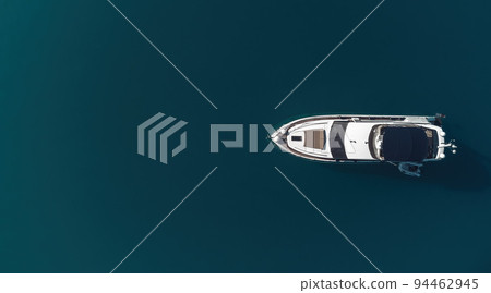 Aerial yacht on calm sea. Luxury cruise trip. View from above of white boat on deep blue water. Aerial view of rich yacht sailing sea. Summer journey on luxury ship. Aerial yacht on calm sea. Luxury cruise trip. View from above of white boat on deep blue water. Aerial view of rich yacht sailing sea. Summer journey on luxury ship. 94462945