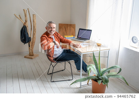 A bearded mature man sitting at the table in the office A bearded mature man sitting at the table in the office 94465762