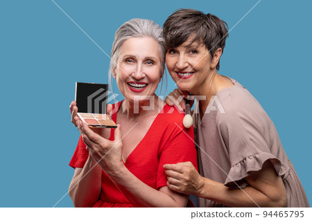 Two women looking involved while doing make up 94465795