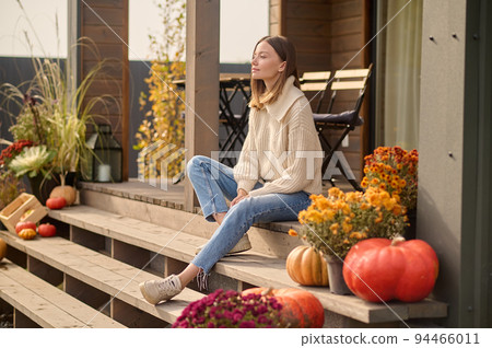 Attractive long-haired lady seated outside the house Attractive long-haired lady seated outside the house 94466011