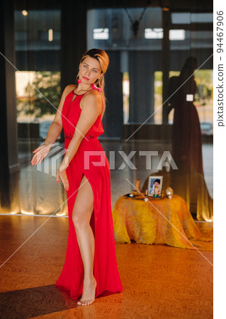 A girl in a red dress moves in a dance meditating indoors . Dynamic dance A girl in a red dress moves in a dance meditating indoors . Dynamic dance 94467906