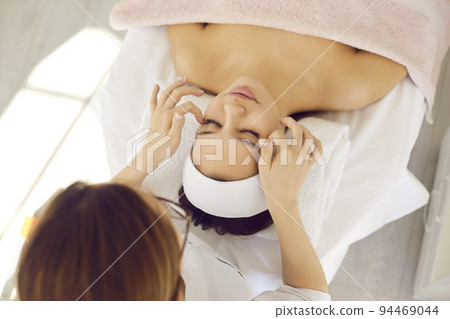 Relaxed young woman getting professional facial massage at a spa or beauty salon Relaxed young woman getting professional facial massage at a spa or beauty salon 94469044