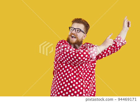 Funny cheerful bearded fat man rejoices and dances dance of success isolated on orange background. 94469171