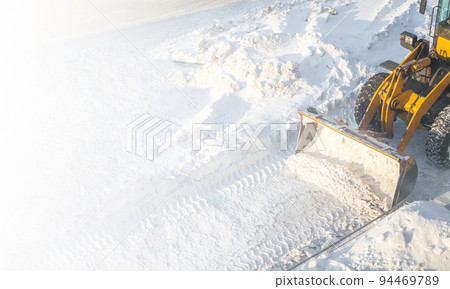 Big orange tractor removes snow from the road and clears the sidewalk 94469789