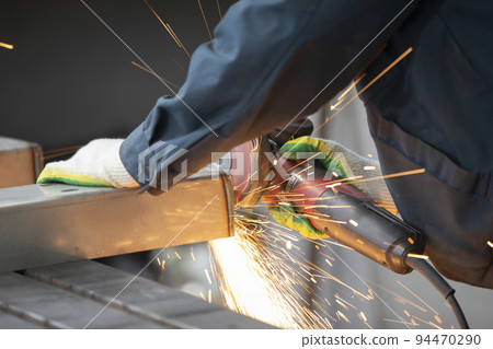 The welder cuts the pipe and fiery sparks fly.Worker cuts gas pipe with grinder, close up 94470290
