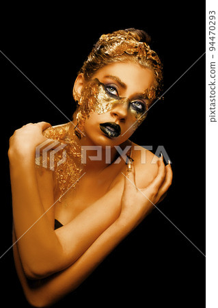 Fashion art Golden skin. Girl Model with Festive Golden Glamor Brilliant Professional Makeup. Creative makeup with golden foil. Fashion art Golden skin. Girl Model with Festive Golden Glamor Brilliant Professional Makeup. Creative makeup with golden foil. 94470293