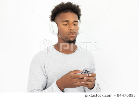 Calm African American man listening to music on smartphone 94470885