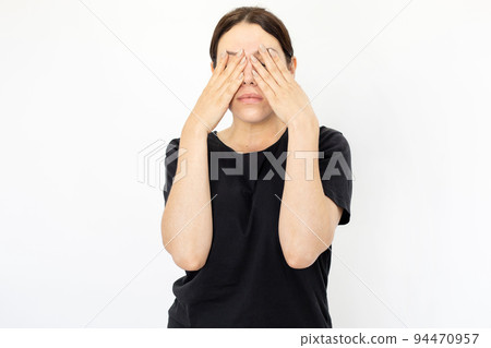 Portrait of young tired woman in black T-shirt covering eyes 94470957