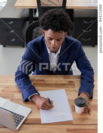 Concentrated man sitting at desk and signing contract 94471006