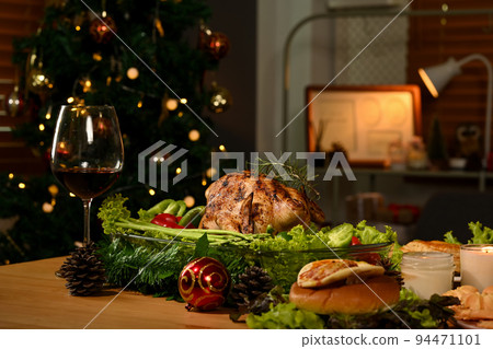 Thanksgiving table with roasted turkey, red wine and sides dishes in decorated room with a Christmas tree 94471101
