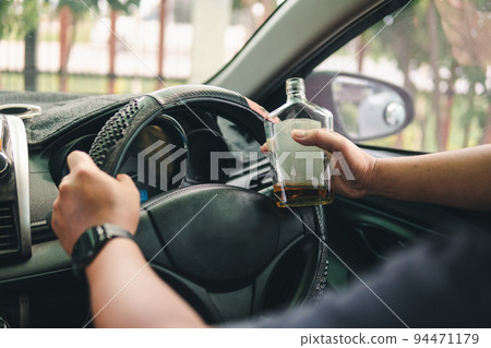 Man drinking alcohol while driving in his car Man drinking alcohol while driving in his car 94471179