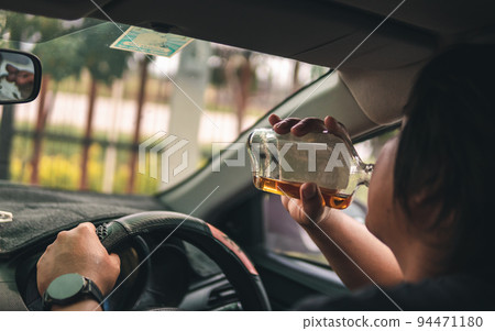 Man drinking alcohol while driving in his car Man drinking alcohol while driving in his car 94471180