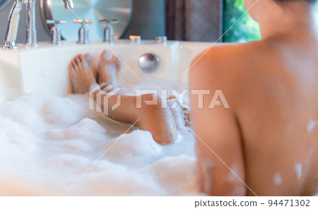 Woman legs in bathtub with foam, Enjoying in spa hotel Woman legs in bathtub with foam, Enjoying in spa hotel 94471302