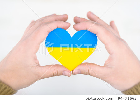 heart in colors of ukrainian flag in hands, concept of help and support for ukraine 94471662