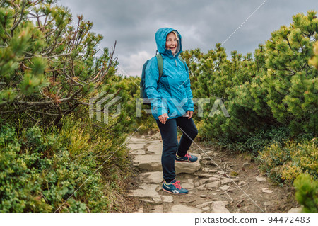 Man and woman hiking at mountains with sports backpack. Travel adventure concept. Group of female friends hiking in nature.  94472483