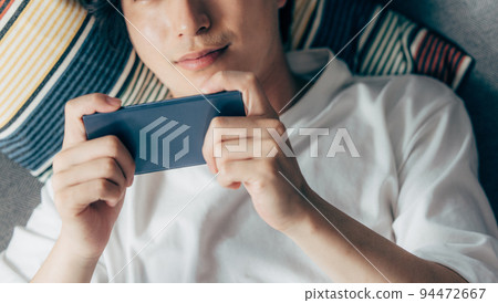 Young man using smartphone on sofa 94472667