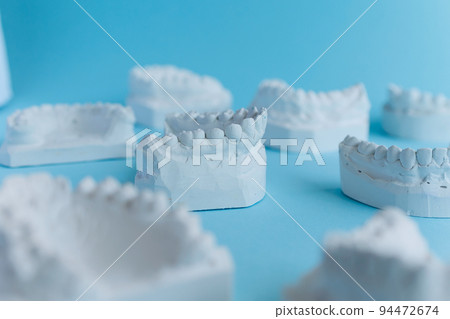 Many plaster models of teeth on a blue background 94472674