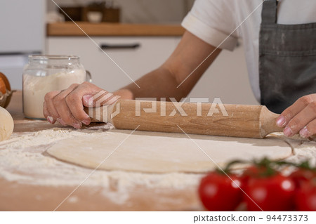 Hands of pastry woman rolling out dough with rolling pin on the table 94473373