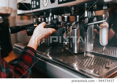 Barista makes aromatic coffee. Process of making latte on a coffee machine in a cafe. 94473437