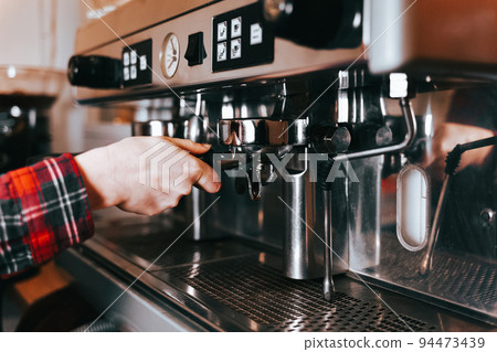 Barista makes aromatic coffee. Process of making latte coffee on a coffee machine in a cafe.. 94473439
