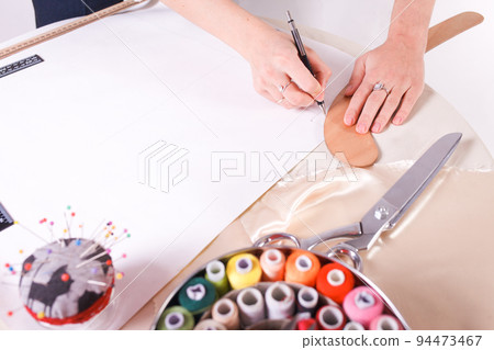 The seamstress makes a pattern for the future product. Sewing workshop. Woman engages in her favorite hobby of sewing. 94473467