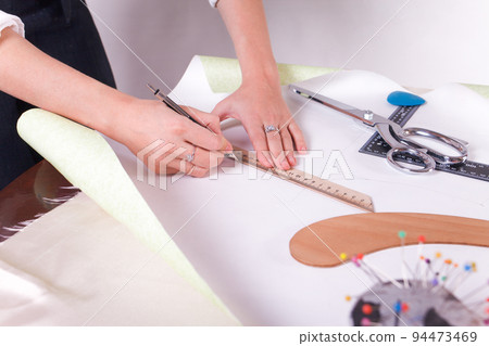 The seamstress makes a pattern for the future product. Sewing workshop. Woman engages in her favorite hobby of sewing.. 94473469