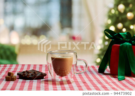 Cup of sweet cocoa on tablecloth and dark chocolate with nuts. 94473902