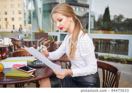 Young student girl writes a diary. Business woman with a pan in hand writes in a notebook Young student girl writes a diary. Business woman with a pan in hand writes in a notebook 94475633