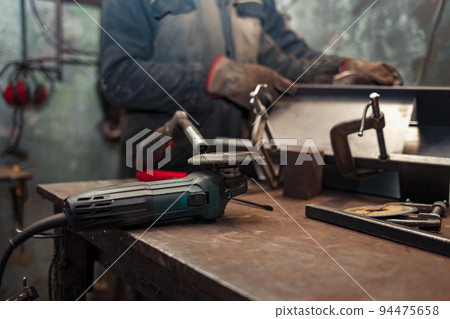 Man clamps iron products into c-clamps. Man works with clamps. Steel workshop concept. 94475658