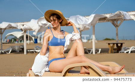 Girl on beach sunbathing sitting on sun lounger 94475773