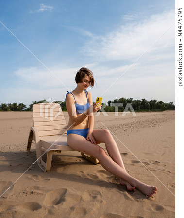 Girl on beach sunbathing sitting on sun lounger 94475795