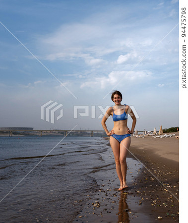 Girl in bikini walks on beach Girl in bikini walks on beach 94475798