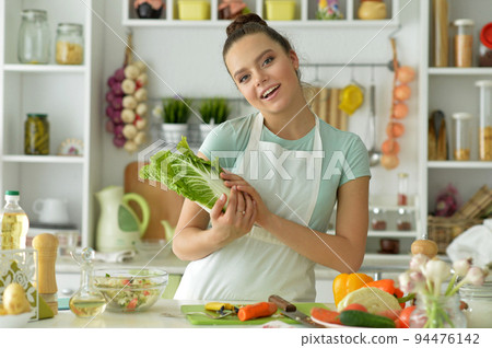 Portrait of young woman making salad at home Portrait of young woman making salad at home 94476142