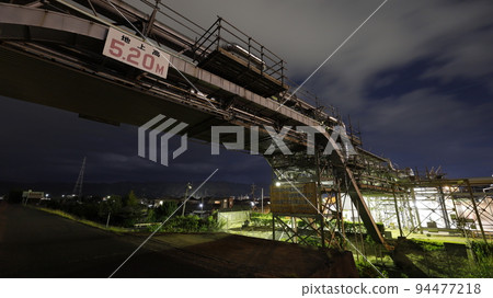 Factory night view seen from the road along the Oze River embankment in Otake City, Hiroshima Prefecture, and the pipeline that crosses the road 94477218