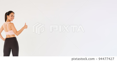 Full length of motivated and satisfied smiling asian female coach, girl athelte in sportswear turn behind to show thumbs-up at camera, ready for productive fitness training, white background Full length of motivated and satisfied smiling asian female coach, girl athelte in sportswear turn behind to show thumbs-up at camera, ready for productive fitness training, white background 94477427