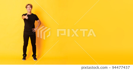 Full-length of friendly handsome korean guy with blond hair, extending hand for handshake, saying hi, standing yellow background 94477437