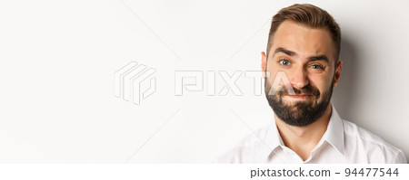 Emotions and people concept. Headshot of skeptical man with beard, grimacing and looking doubtful, standing displeased against white background 94477544