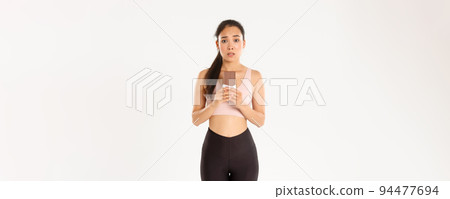 Sport, wellbeing and active lifestyle concept. Indecisive cute asian girl in workout clothing, looking hesitant at chocolate bar, trying resist temptation as losing weight on diet 94477694