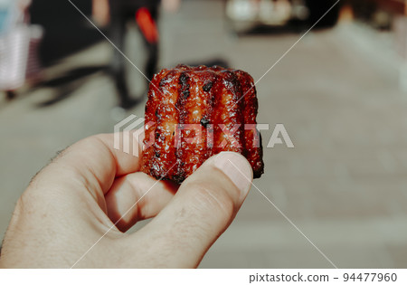 man has a french canele pastry in his hand 94477960