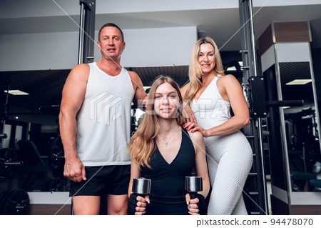 Mother, father and teen daughter training together in a gym 94478070