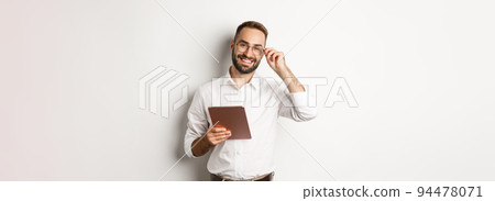Confident business man working on digital tablet, smiling happy, standing over white background 94478071