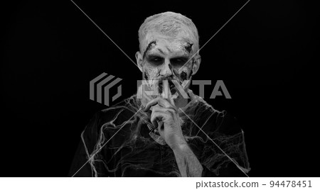 Halloween zombie man presses index finger to lips makes silence gesture sign do not tells secret Halloween zombie man presses index finger to lips makes silence gesture sign do not tells secret 94478451